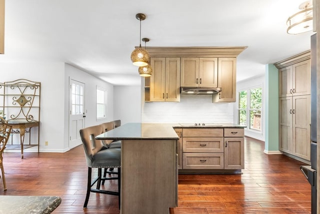 kitchen featuring tasteful backsplash, dark hardwood / wood-style flooring, a center island, and a kitchen bar