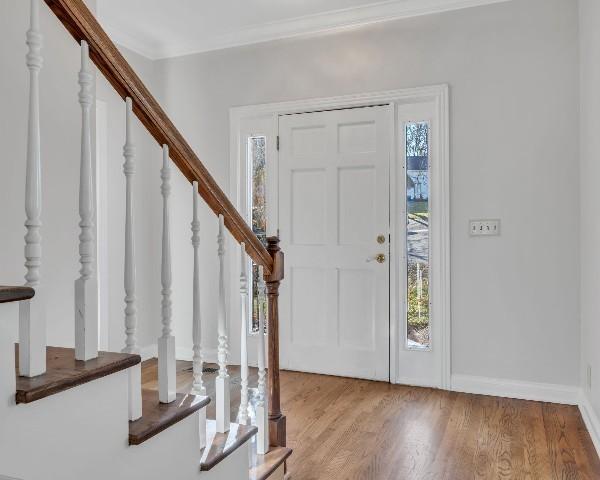 foyer with crown molding and light hardwood / wood-style floors