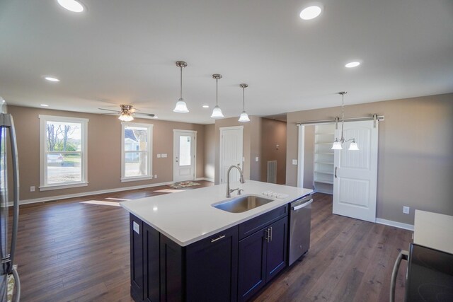 kitchen featuring stainless steel dishwasher, sink, decorative light fixtures, a center island with sink, and dark hardwood / wood-style floors