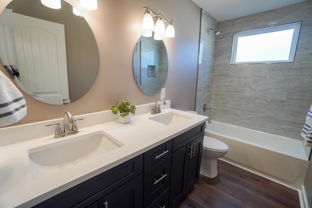 full bathroom with vanity, hardwood / wood-style floors, tiled shower / bath, and toilet