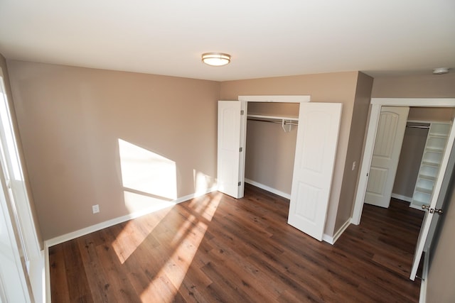 unfurnished bedroom featuring two closets and dark hardwood / wood-style floors