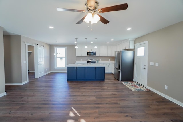 kitchen with appliances with stainless steel finishes, dark hardwood / wood-style flooring, white cabinetry, and hanging light fixtures