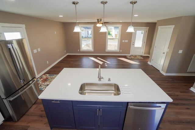 kitchen with blue cabinetry, appliances with stainless steel finishes, dark wood-type flooring, and an island with sink