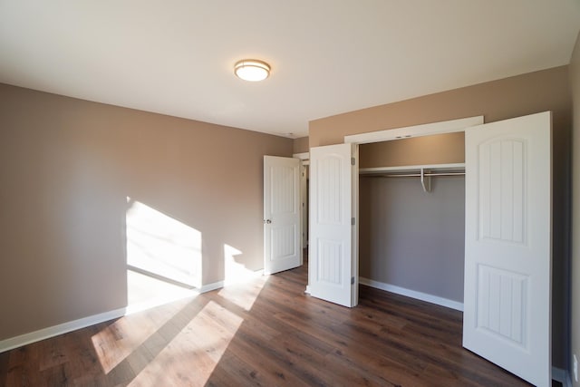 unfurnished bedroom with dark hardwood / wood-style floors and a closet