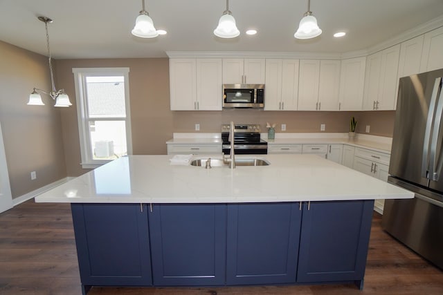 kitchen with appliances with stainless steel finishes, a center island with sink, white cabinetry, and pendant lighting