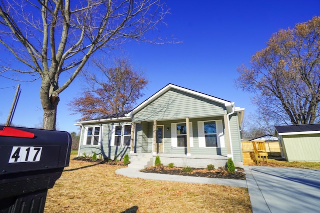 bungalow-style home featuring covered porch and a storage shed