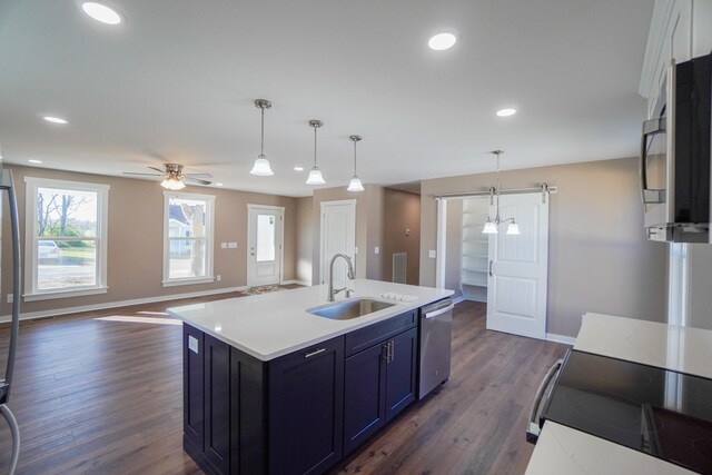 kitchen featuring appliances with stainless steel finishes, decorative light fixtures, dark wood-type flooring, and sink