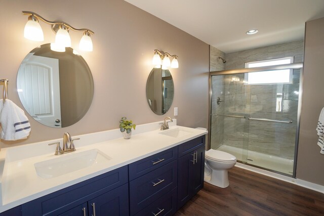 bathroom featuring wood-type flooring, vanity, toilet, and a shower with door