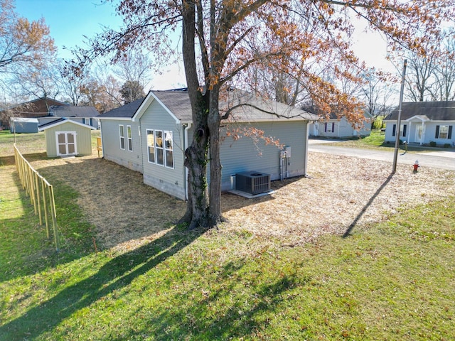 exterior space featuring a lawn, central AC unit, and a storage unit