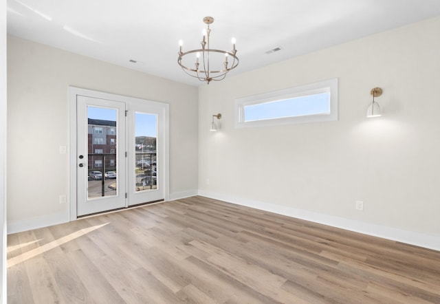 empty room featuring light hardwood / wood-style flooring and an inviting chandelier