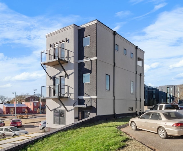 view of side of property with a balcony and a yard