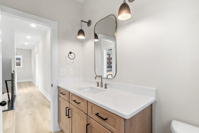 bathroom with toilet, vanity, and hardwood / wood-style flooring