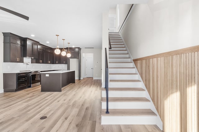 kitchen featuring backsplash, light wood-type flooring, sink, decorative light fixtures, and a kitchen island