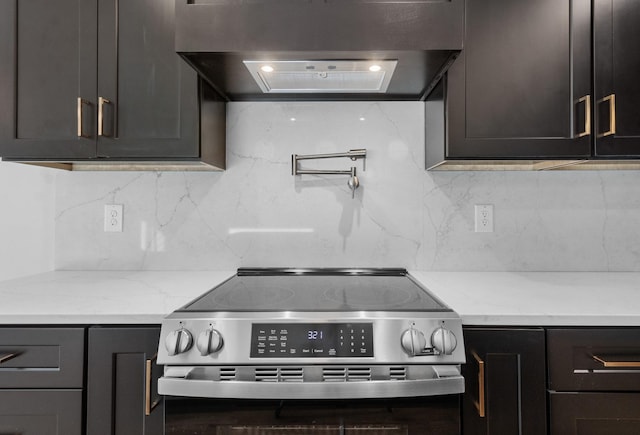 kitchen with ventilation hood, light stone countertops, high end range, and tasteful backsplash