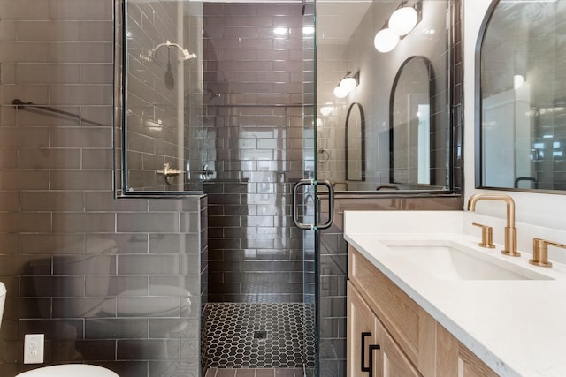 bathroom featuring vanity, toilet, and a shower with door