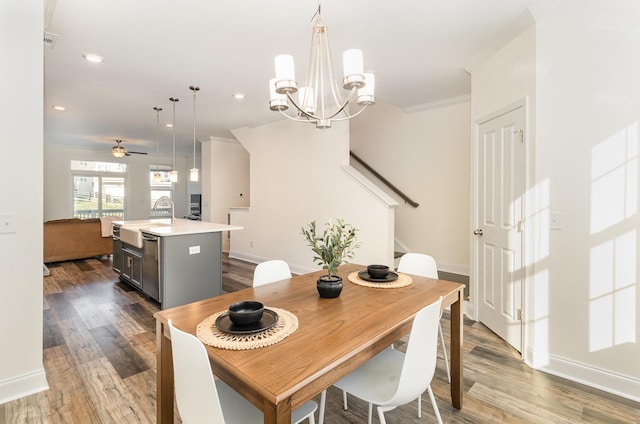 dining room featuring ceiling fan with notable chandelier, wood-type flooring, sink, and ornamental molding