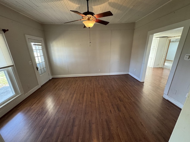 empty room with a wealth of natural light, dark hardwood / wood-style flooring, and ceiling fan