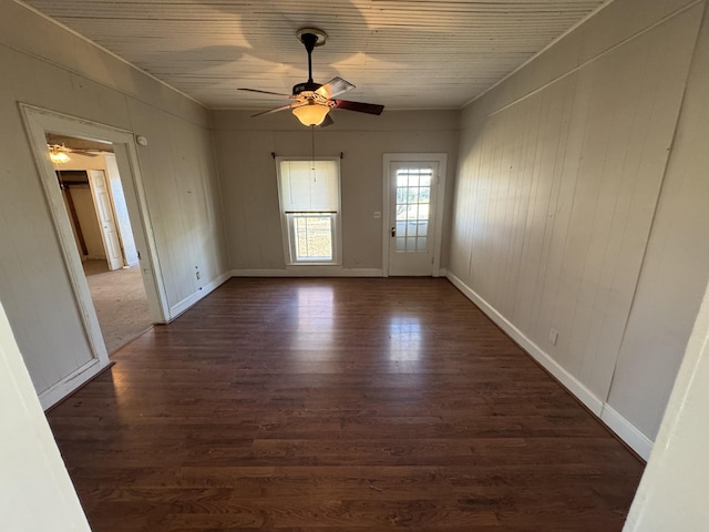 unfurnished room with dark hardwood / wood-style floors, ceiling fan, and wood walls