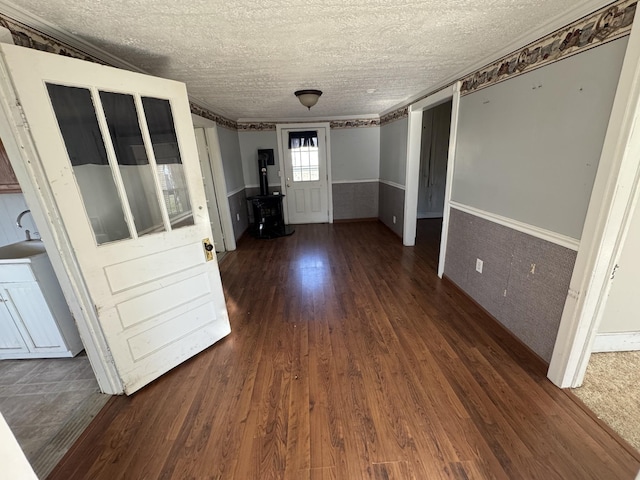 interior space featuring a textured ceiling, ornamental molding, and dark wood-type flooring