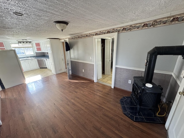 unfurnished living room with a wood stove, ornamental molding, a textured ceiling, and hardwood / wood-style flooring