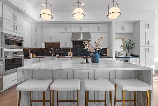 kitchen featuring white cabinetry, pendant lighting, a kitchen island, and extractor fan