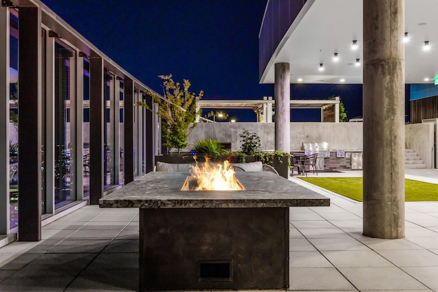 patio at twilight featuring area for grilling, an outdoor fire pit, and a grill