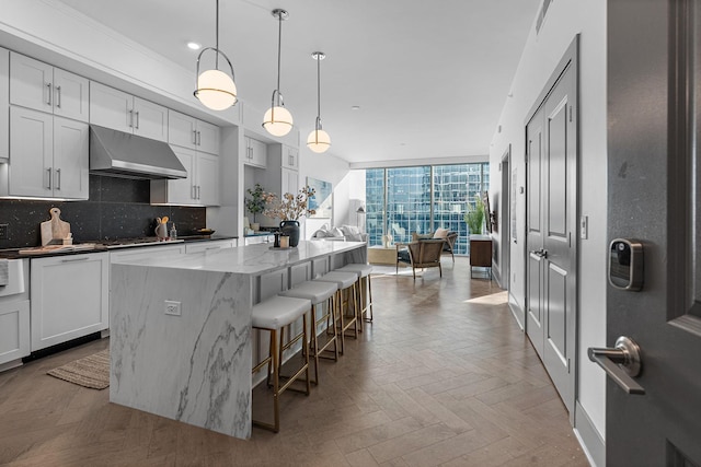 kitchen featuring a center island, hanging light fixtures, expansive windows, backsplash, and light parquet floors