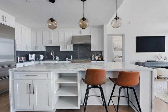 1616 W End Ave Unit 2011, Nashville, TN 37203 - kitchen featuring under cabinet range hood, tasteful backsplash, a kitchen island, open shelves, and white cabinets