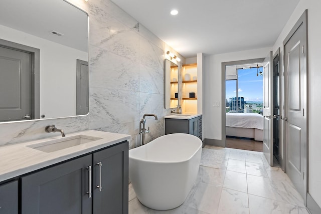 1616 W End Ave Unit 2011, Nashville, TN 37203 - ensuite bathroom featuring tile walls, two vanities, a freestanding bath, marble finish flooring, and recessed lighting