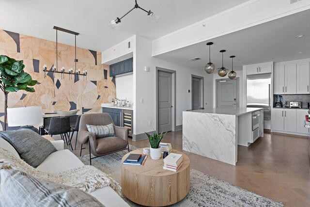 living room featuring dark parquet flooring, wine cooler, and an inviting chandelier