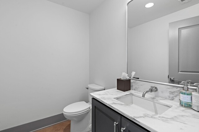 bathroom featuring vanity, hardwood / wood-style flooring, and toilet