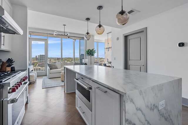 kitchen with pendant lighting, high end white range oven, white cabinetry, and exhaust hood