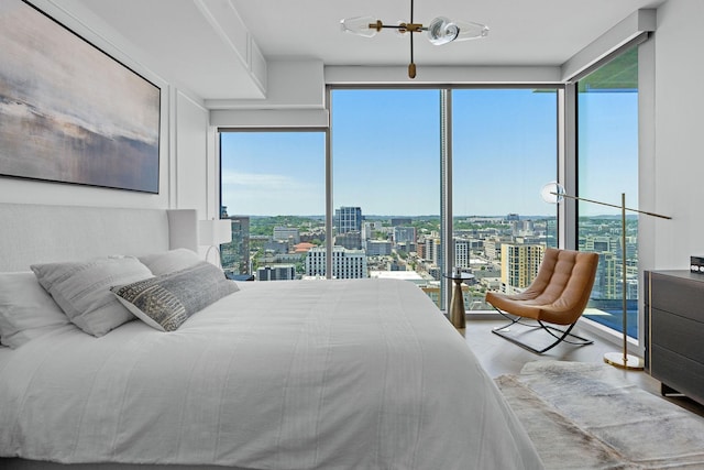 bedroom with expansive windows, light hardwood / wood-style flooring, and multiple windows