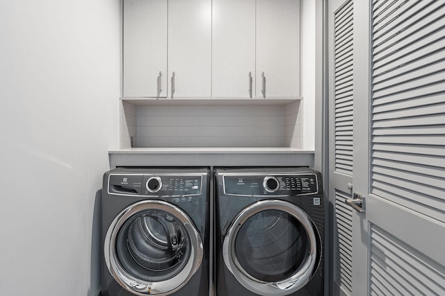 washroom with washing machine and clothes dryer and cabinets