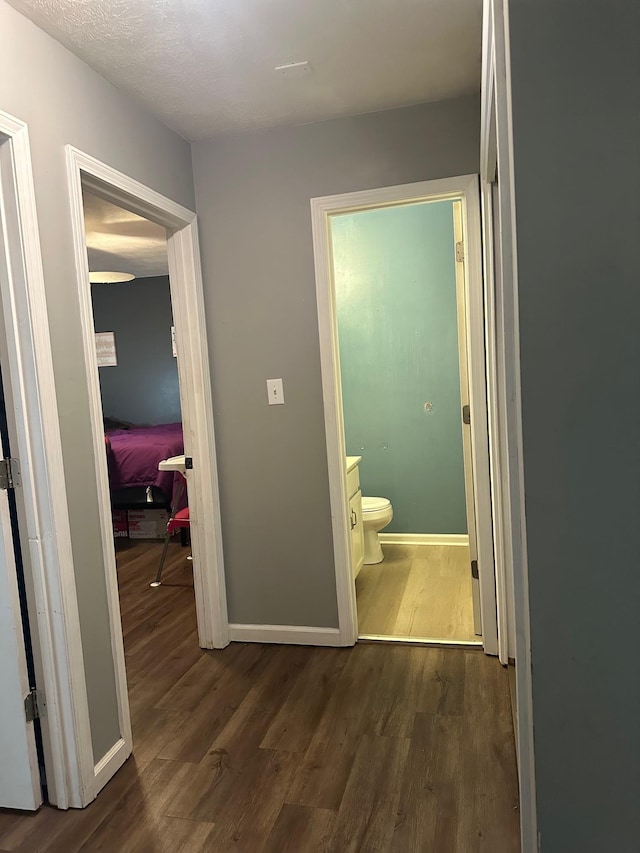 corridor with a textured ceiling and dark hardwood / wood-style floors