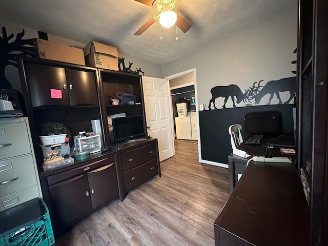 home office featuring a textured ceiling, light hardwood / wood-style floors, ceiling fan, and washing machine and clothes dryer