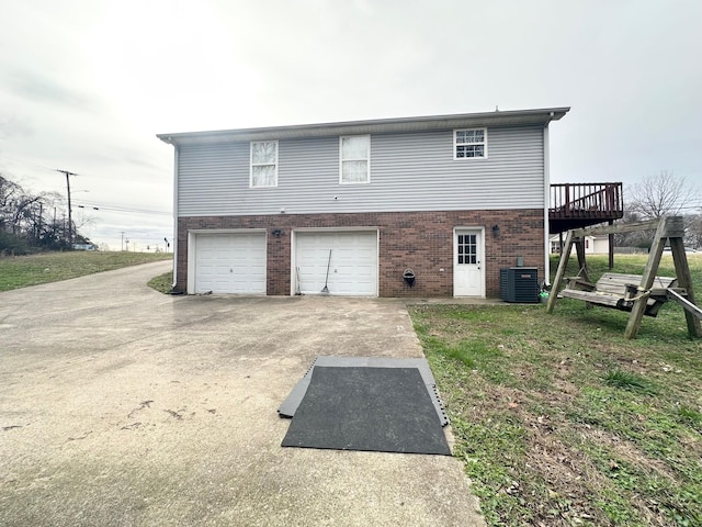 rear view of house featuring cooling unit, a garage, a deck, and a yard