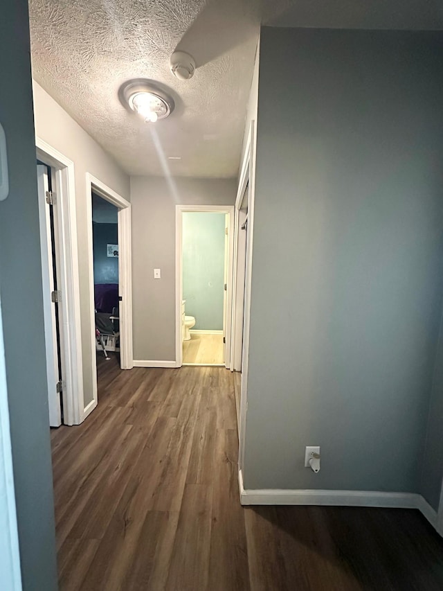 hall with a textured ceiling and dark wood-type flooring