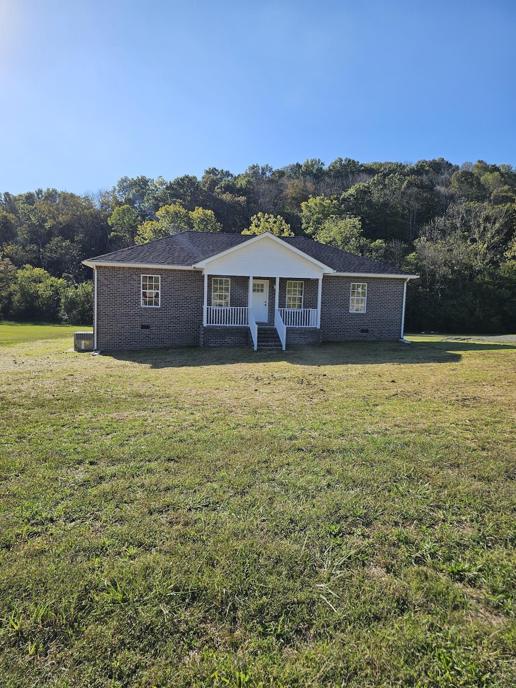 ranch-style house featuring a porch, central air condition unit, and a front lawn