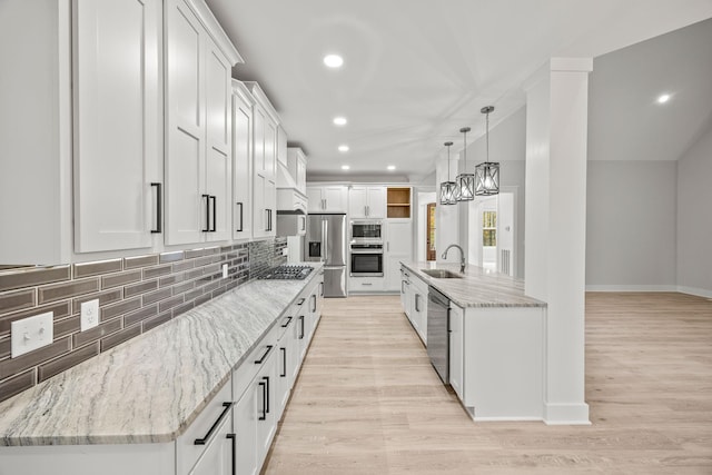 kitchen featuring appliances with stainless steel finishes, light wood-type flooring, sink, a center island with sink, and white cabinets