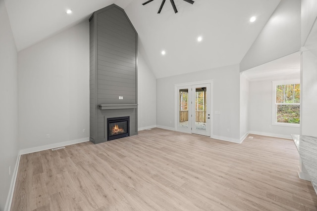 unfurnished living room with a fireplace, light wood-type flooring, high vaulted ceiling, and a wealth of natural light