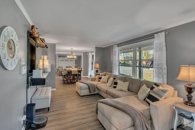 living room with crown molding, light hardwood / wood-style floors, and an inviting chandelier