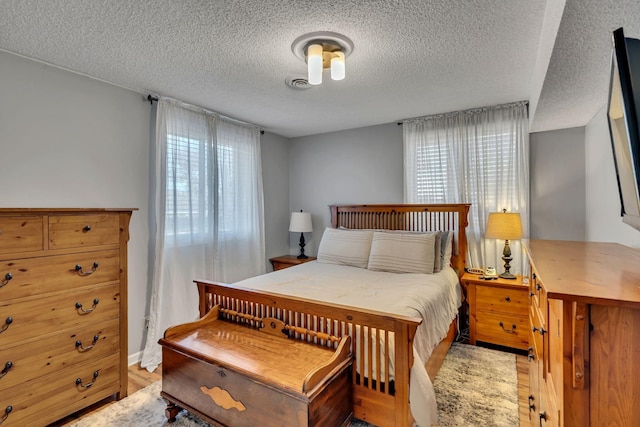 bedroom with light hardwood / wood-style floors and a textured ceiling