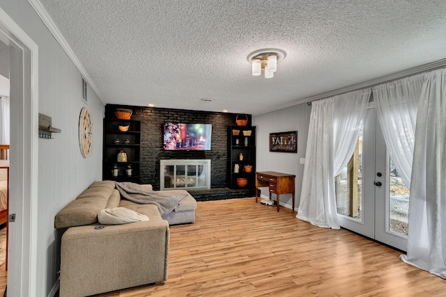 living room with a brick fireplace, crown molding, a textured ceiling, and hardwood / wood-style flooring