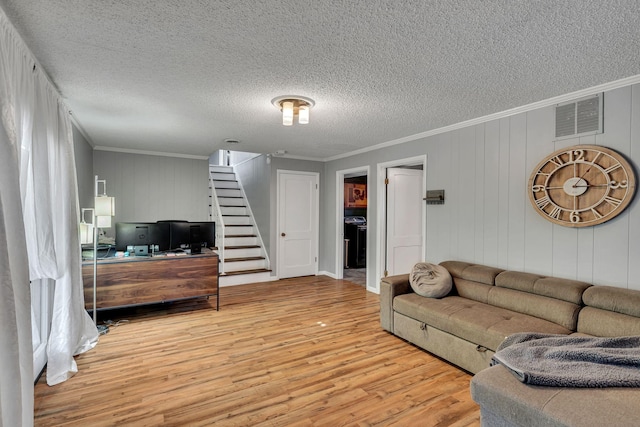 living room featuring hardwood / wood-style flooring, ornamental molding, and a textured ceiling