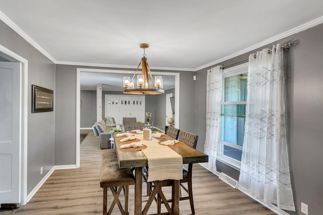 dining space with hardwood / wood-style flooring, ornamental molding, and a chandelier