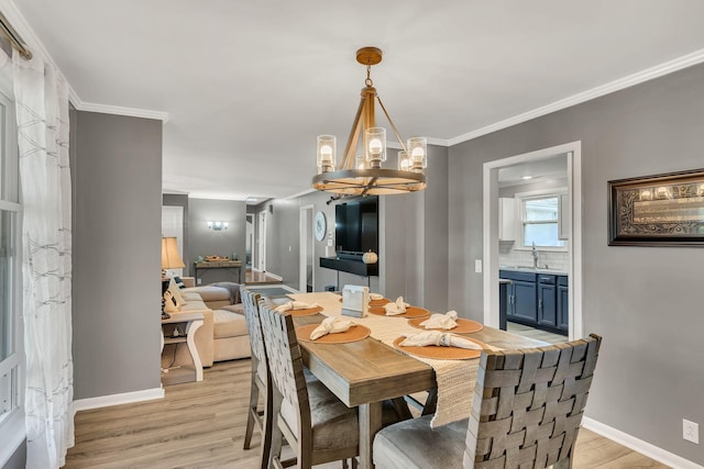 dining room with a chandelier, light hardwood / wood-style flooring, ornamental molding, and sink