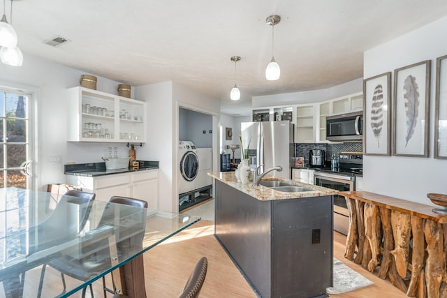 kitchen with white cabinetry, sink, hanging light fixtures, a kitchen island with sink, and appliances with stainless steel finishes