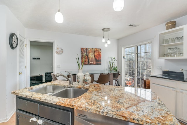 kitchen featuring white cabinets, pendant lighting, light stone countertops, and sink