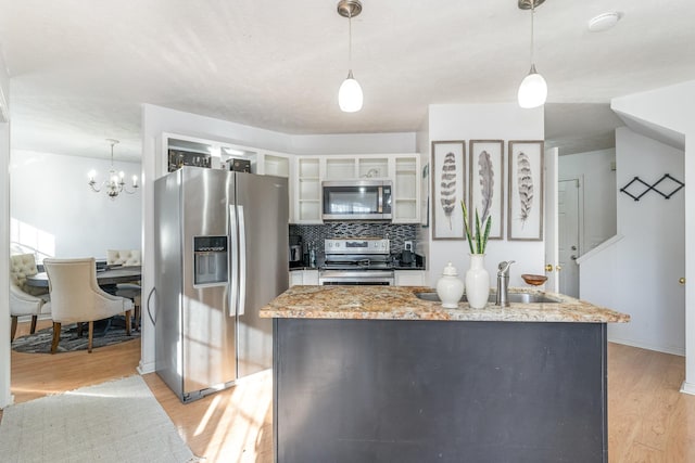 kitchen with white cabinets, decorative light fixtures, stainless steel appliances, and light hardwood / wood-style flooring